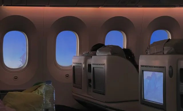 A quiet business-class cabin with lie-flat seats and window shades at dusk