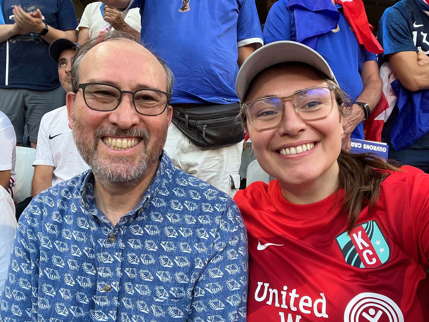 Emily in a red soccer jersey with a friend in the stands at the Lyon stadium